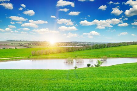 green field, lake and sunriseの写真素材
