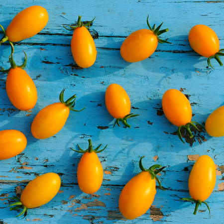yellow small tomatoes on blue wooden surfaceの写真素材