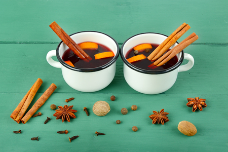 Hot red mulled wine on wooden background with christmas spices, orange slice, anise and cinnamon sticks, close up.の写真素材