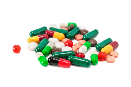 Assorted pharmaceutical medicine pills, tablets and capsules isolated on white background. Shallow depth of field. Focus on the foreground.の写真素材