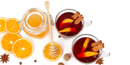 Hot red mulled wine, bee honey, slices of oranges and spices isolated on white background. Flat lay, top view. Free space for text. Wide photo.の写真素材