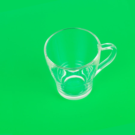 A glass empty transparent cup on a bright green background. Flat lay, top view.の写真素材