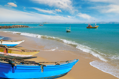 Fishing boat on the sandy shore against a background the ocean and blue sky.の写真素材