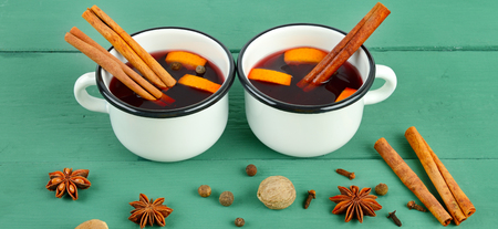 Hot red mulled wine on wooden background with spices, orange slice, anise and cinnamon sticks, close up. Wide photo.の写真素材