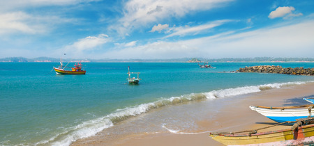 Fishing boat on the sandy shore against a background the ocean and blue sky. Wide photo.の写真素材