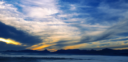 Bright sunrise, the mist in a mountain valley and mountain peaks on the horizon. Wide photo.の写真素材