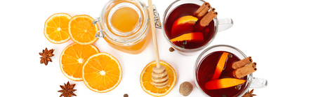 Hot red mulled wine, bee honey, slices of oranges and spices isolated on white background. Flat lay, top view. Free space for text. Wide photo.の写真素材