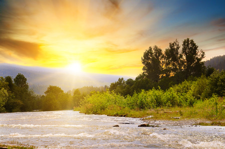 Bright sunrise in the mountains of the Carpathians, Ukraine. The rays of the sun are reflected in the mountain river. Concept ecology protection. Explore the world's beauty.の写真素材