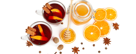 Hot red mulled wine, bee honey, slices of oranges and spices isolated on white background.の写真素材
