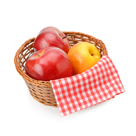 Red and yellow apples in a wicker basket isolated on white background.の写真素材