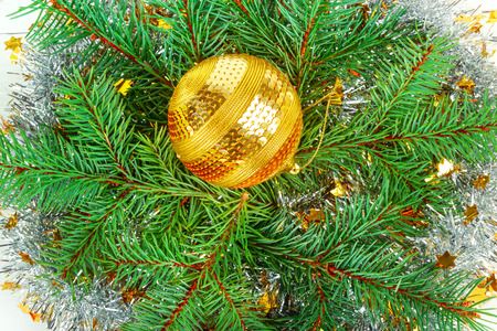 Christmas or New Year ornament. Bright golden ball on the background of a wreath of spruce twigs. Flat lay, top view.の写真素材