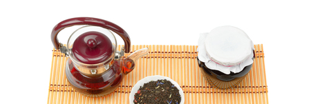 Teapot, jam jar and tea leaves isolated on whiteの写真素材