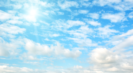 Bright sun on blue sky with white clouds.の写真素材