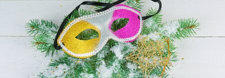 Christmas ornament. A wreath of fir branches, a mask and a decorative star on a white wooden background. Wide photo.の写真素材