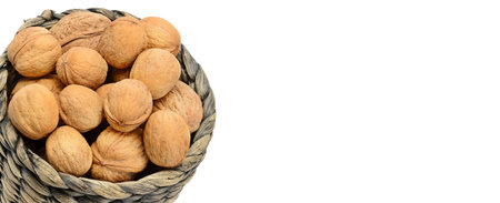 Walnuts in Wicker basket isolated on white background. Free space for text. Wide photo .