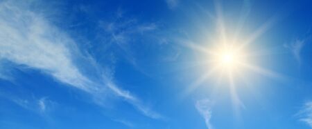 Couds in the blue sky. Bright midday sun illuminates the space. Wide photo .の写真素材