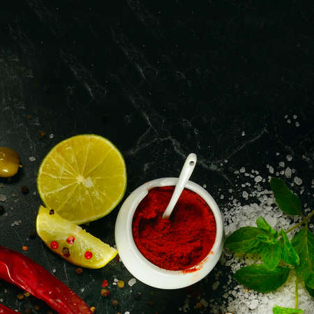 Chili pepper, cooking sea salt, lemon and mint on a black background. Place for your text.の写真素材