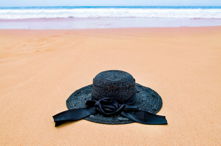 Womens beach hat on sand on the beach, blue sea, and blue sky on background, copy space for text....