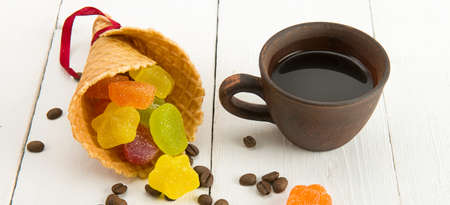 Cup of coffee ,waffle cone, roasted coffee beans and marmalade candy on white background. wide photo.の写真素材
