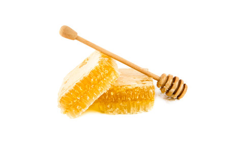 Sweet honeycomb and wooden drizzler isolated on white background.