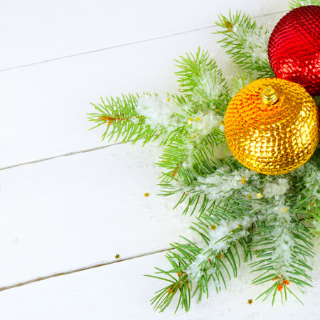 A sprig of fir, Christmas multicolored balls and snow on a white wooden background. Free space for text.の写真素材