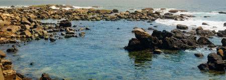 Picturesque tropical beach with boulders. Wide photo.