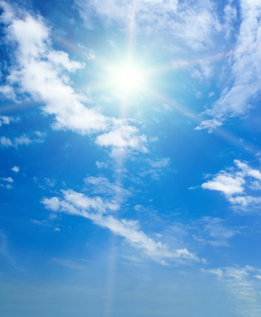 Blue sky with white clouds and bright sun. Vertical photo.の写真素材