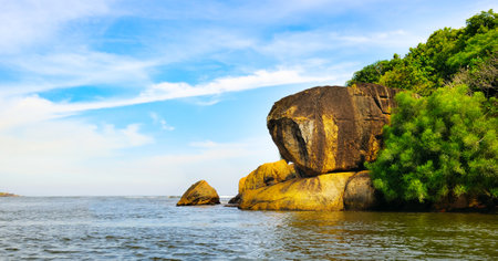 Sea, rock formation and boulder, exotic tree and bush on Secret Island, Beruwala, Sri Lanka. Wide photo.の写真素材