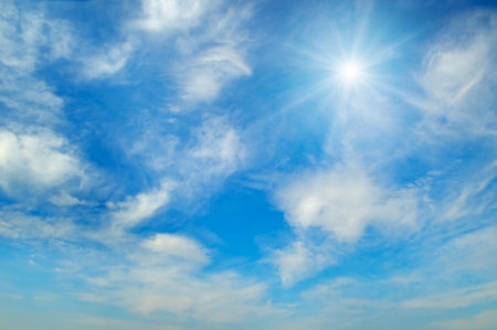Bright sun and white clouds in clear blue sky on summer day.の写真素材