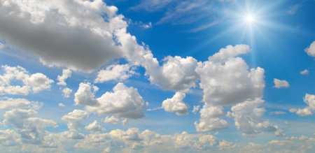Bright sun and white clouds in clear blue sky on summer day. Wide photo.の写真素材