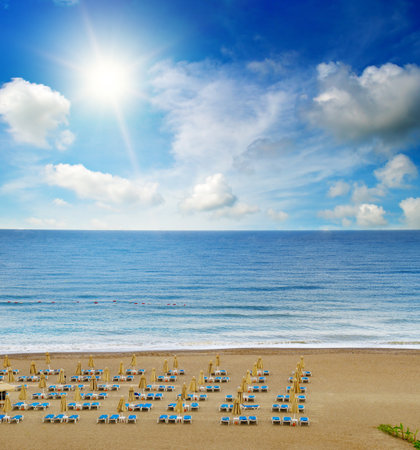 Rows of sun loungers and umbrellas set against the turquoise sea and sandy shoreの写真素材