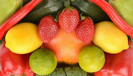 A vibrant, full-frame flat lay of assorted fruits and vegetables displays a rainbow of color and texture. The healthy composition, featuring strawberries, citrus, and peppers, is perfect for themes of nutrition and fresh produce.の写真素材