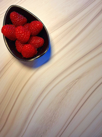 Raspberries in a bowl on a wooden background, top view
