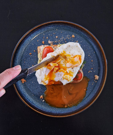 Egg benedict with tomato and cheese in a blue plate