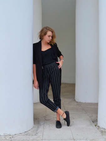 A sexy young woman in a business black suit is standsの写真素材