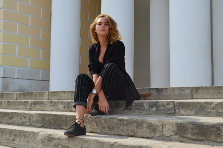 A sexy young woman in a business black suit is sitting