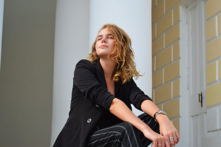 A sexy young woman in a business black suit is sitting