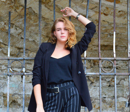 A pretty teenage girl n a business black suit is stands