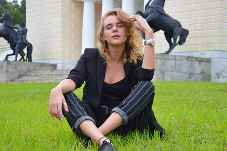 A pretty teenage girl n a business black suit is sitting