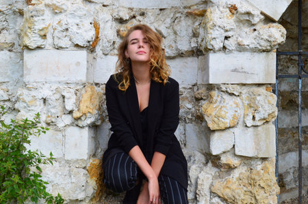 A pretty teenage girl n a business black suit is sitting