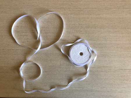 Heart made of white ribbon on a wooden background.