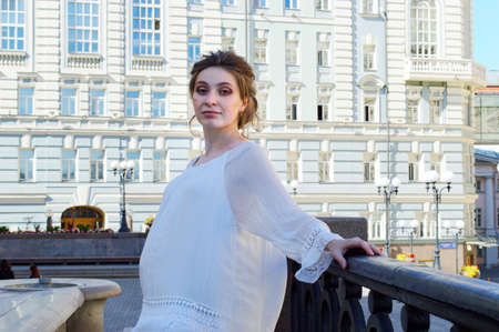 Pregnant girl in a white blouse. Blonde girl. Young girl. Girl in blue jeans.の写真素材