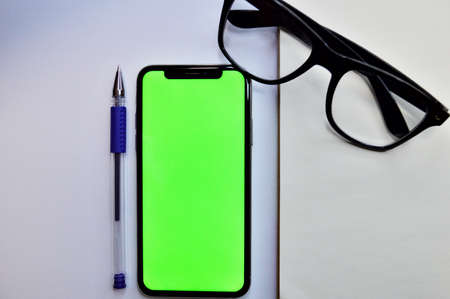 Mix of office supplies and gadgets on a wooden table background. View from above. Wrist Watch, notebook, pen, glasses and phone on wooden backgroundの写真素材