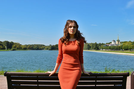 Young girl in orange dress stands near the water