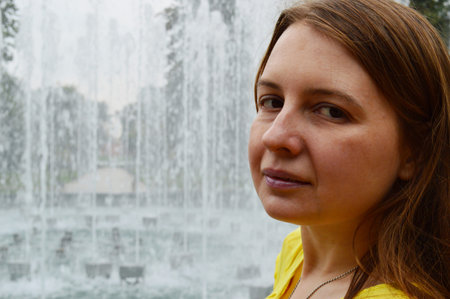 Woman with dark hair in a yellow T-shirt near the fountain