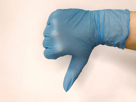 Hand in blue glove isolated on white with thumb down.