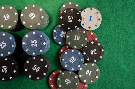 game and entertainment concept - close up of casino chips on green table