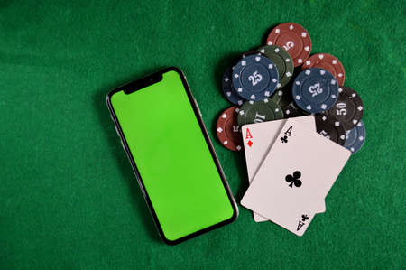 Poker background - chips, cards and phone with a green screen on green tableの写真素材