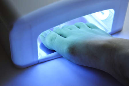 Pedicure foot and nails treatment with UV lamp. Spa at homeの写真素材