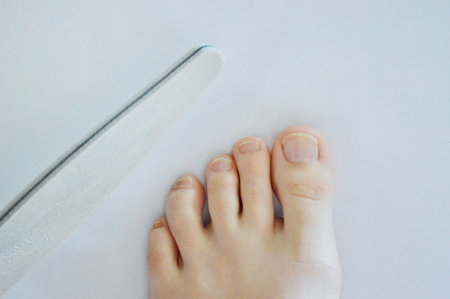Female feet legs nail file in hands beauty pedicure on white background isolation. Spa at home